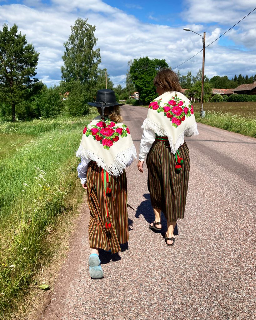 Lisa Kriga med dotter går längs Nusnäs Bygata i Norrbottensdräkt.